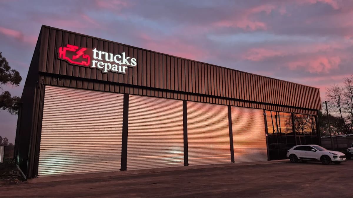 Fachada del local de Trucks Repair en Chillán Viejo al atardecer, con letrero iluminado